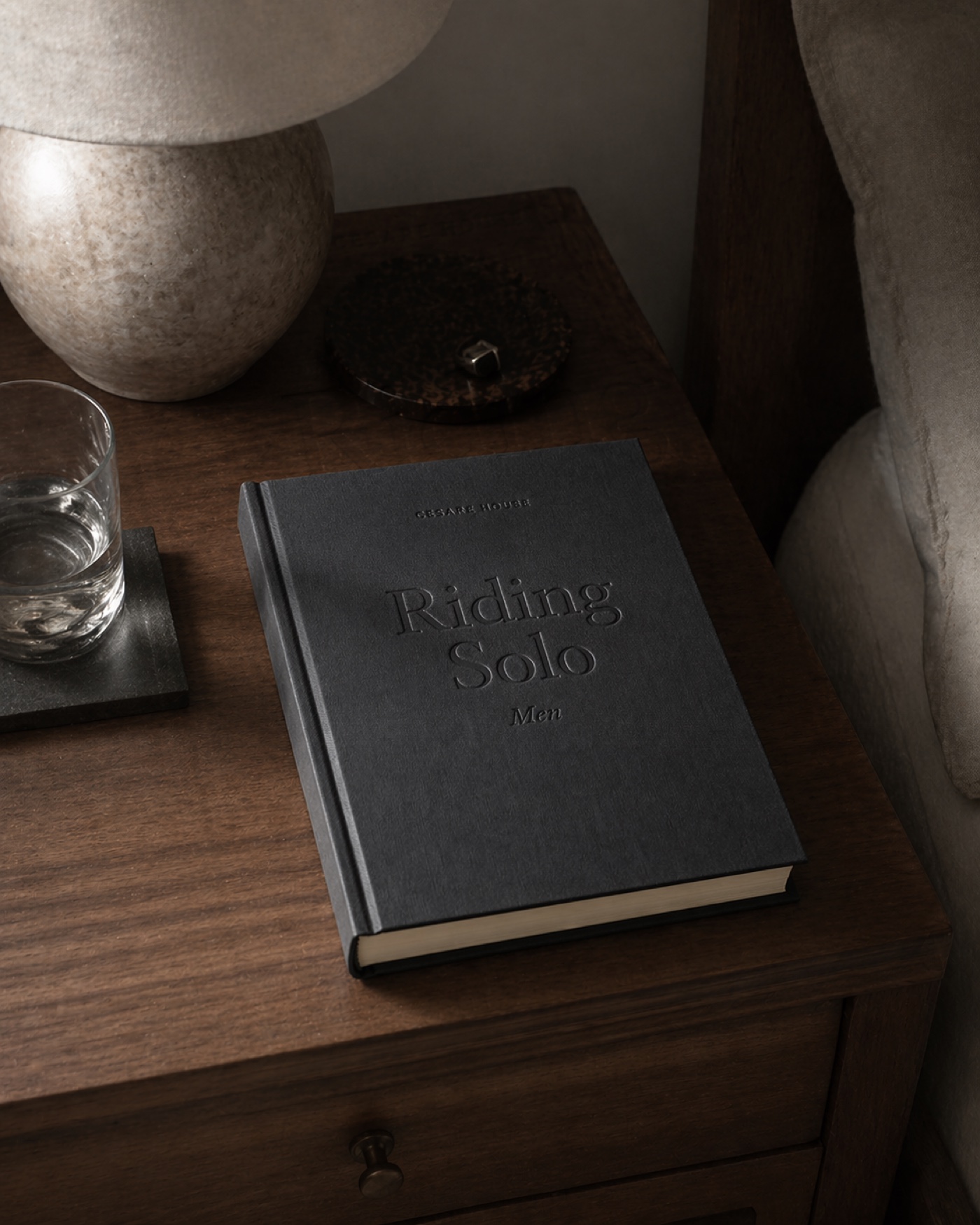 Riding Solo: Men, a clothbound hardcover book with blind-embossed title, resting on a wooden nightstand